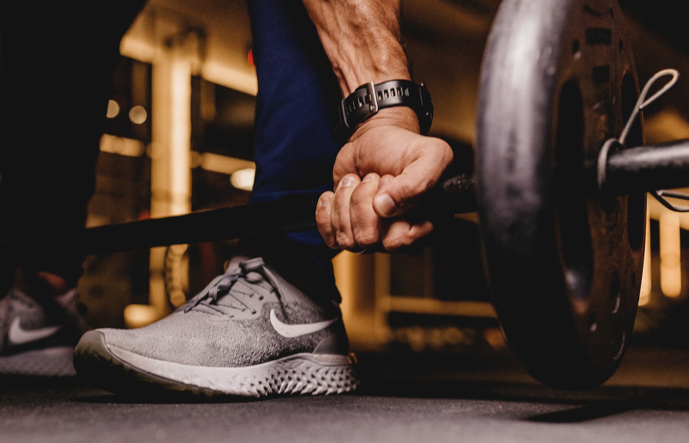 Athlete gripping a barbell in a moody, dramatic gym setting